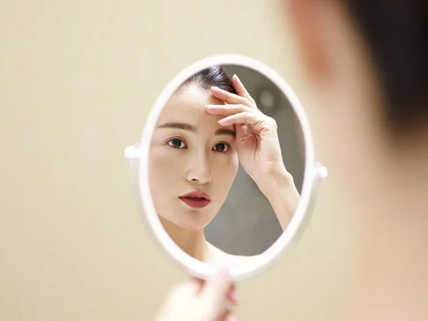 Young asian woman looking at self in mirror — Stock Photo, Image
