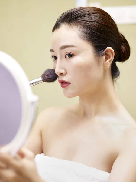 Mladá asijská žena při pohledu do zrcadla při líčení — Stock fotografie