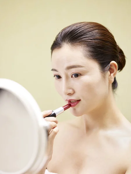 年轻的亚洲妇女在照镜子时涂抹口红 — 图库照片