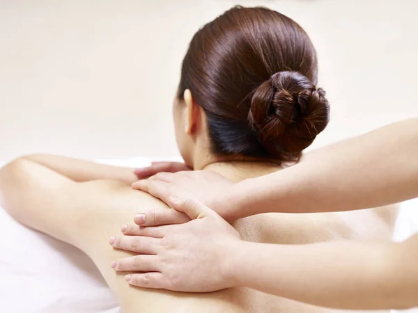 Mãos de massagista realizando massagem no jovem mulher asiática — Fotografia de Stock