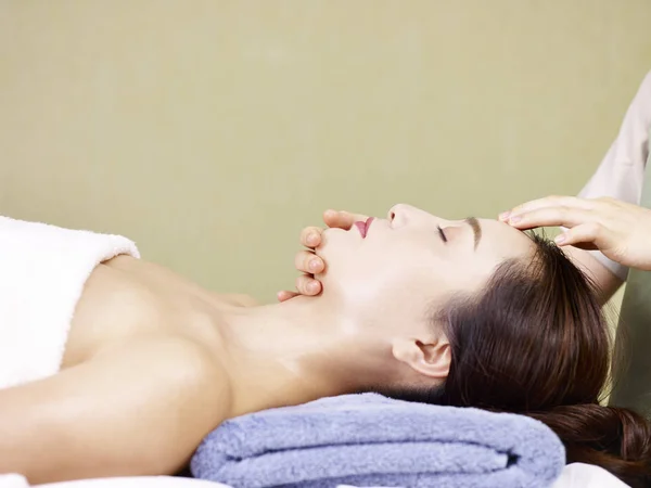 Mladá asijská žena přijímá masáž obličeje ve spa salonu — Stock fotografie