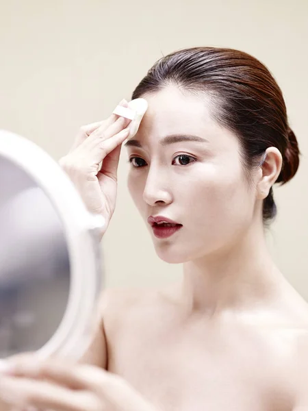 Mladá asijská žena při pohledu do zrcadla při čištění obličeje — Stock fotografie