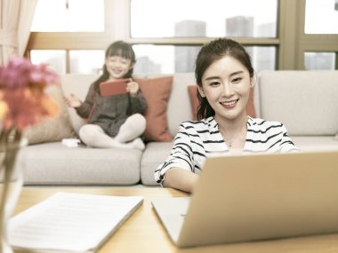 Genç Asyalı anne evde çalışıyor.