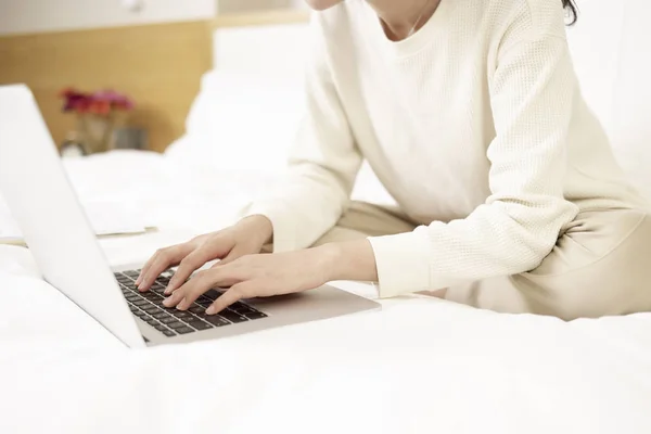 Asiatische Frau mit Laptop auf Bett — Stockfoto