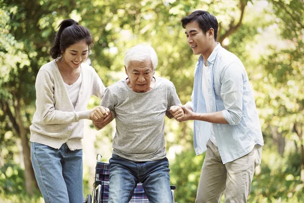 Young asian couple helping old man stand up — Stock Photo, Image