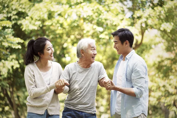 Young asian couple helping old man walk — Stock Photo, Image
