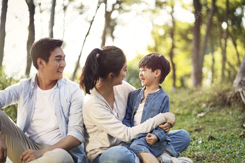 asian family with one child relaxing in park