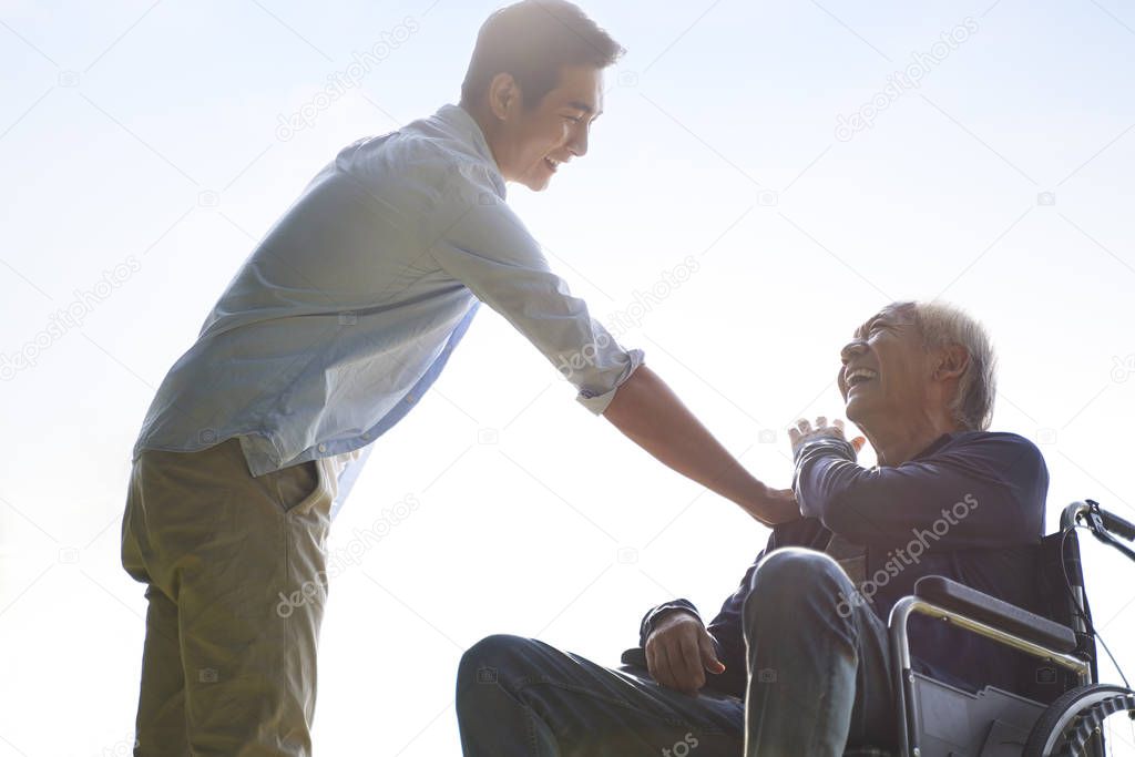 asian son giving father a pat on the shoulder