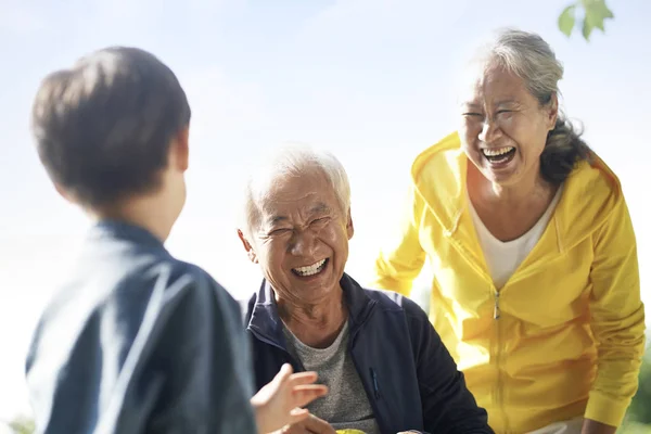 Asyalı büyükanne ve büyükbaba ve torun parkta eğleniyorlar. — Stok fotoğraf