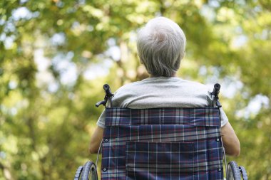 Çinli yaşlı adam tekerlekli sandalyede oturuyor.