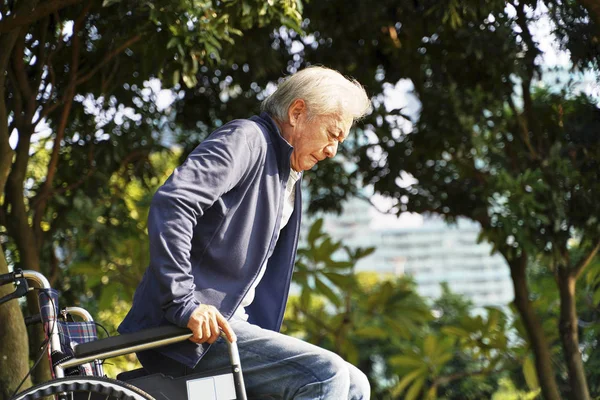 Asian senior man trying to stand up from wheel chair — Stock Photo, Image