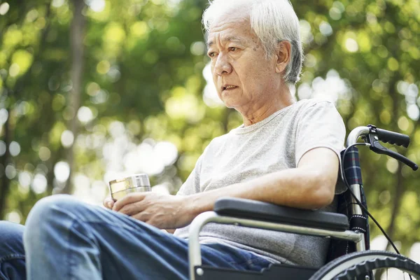 Üzgün Asyalı yaşlı adam tekerlekli sandalyede oturuyor. — Stok fotoğraf