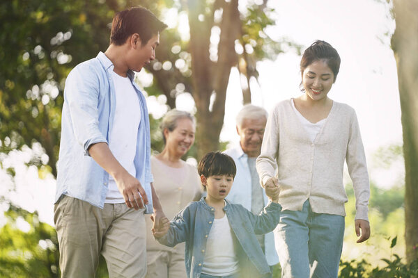 three generation asian family walking in park