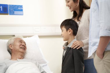Asyalı aile dedeyi hastanede ziyaret ediyor.