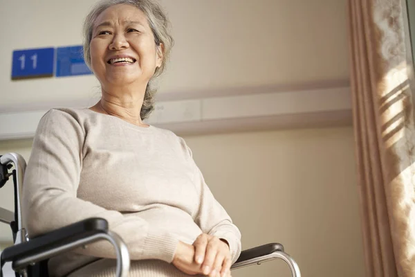 Счастливая старуха, сидящая в инвалидной коляске в доме престарелых — стоковое фото