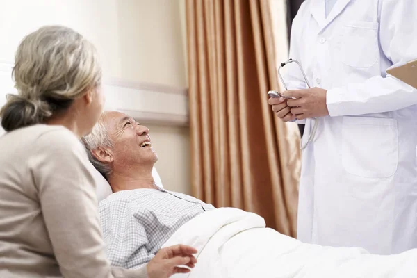 Азиатский пожилой человек лежит в постели и разговаривает с врачом на войне в госпитале — стоковое фото
