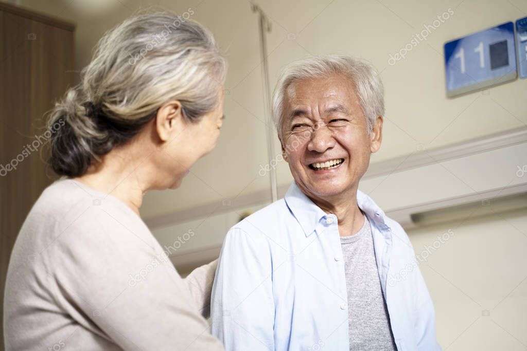 happy asian old couple chatting in hospital ward