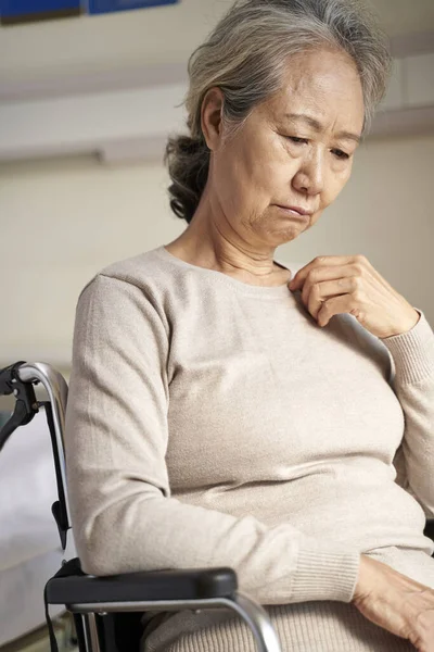 Грустная пожилая азиатка, сидящая в инвалидной коляске в доме престарелых — стоковое фото