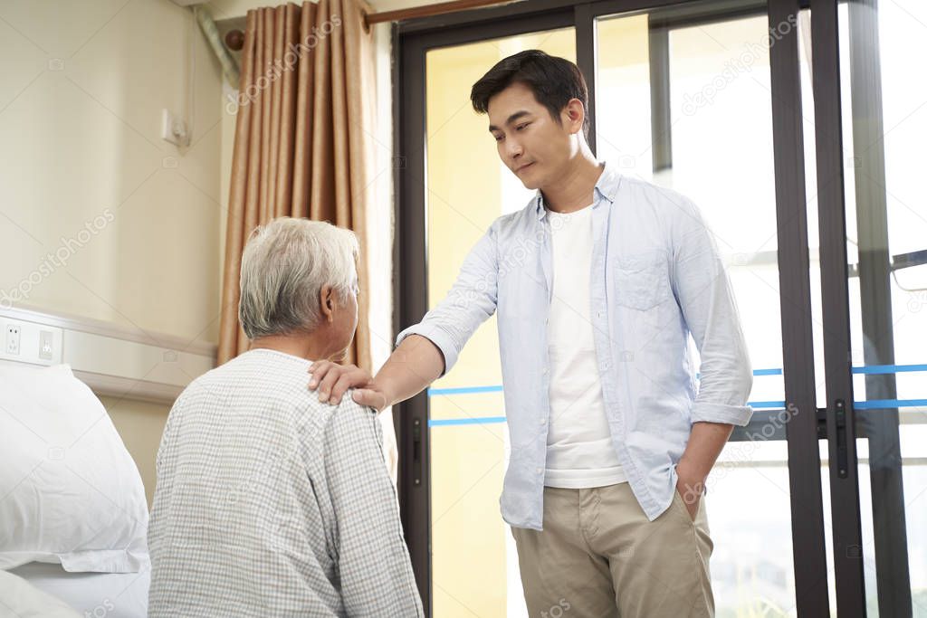 asian adult son visiting father in hospital or nursing home