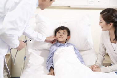 Genç Asyalı doktor çocuk hasta ve annesiyle konuşuyor.