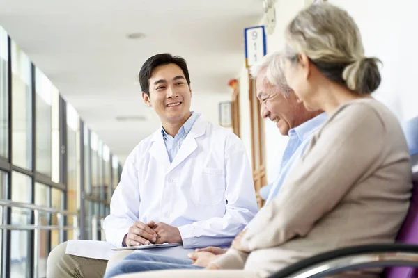 Young asian doctor talking to senior couple patients in hospital — Stock Photo, Image