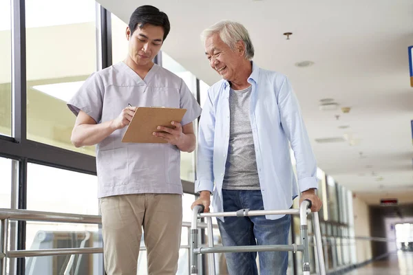 Young asian physical therapist working with old man — Stock Photo, Image