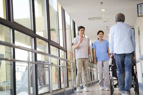 Asiático empregado cumprimentando residentes no corredor de lar de idosos — Fotografia de Stock