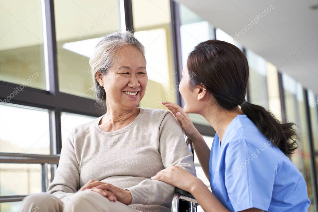 friendly asian staff talking to senior resident in nursing home