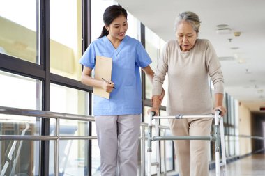 young asian physical therapist working with senior woman on walking with a walker