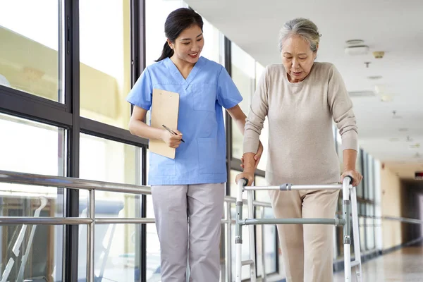 Junge Asiatische Physiotherapeutin Arbeitet Mit Seniorin Beim Gehen Mit Rollator — Stockfoto