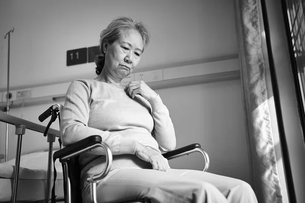 悲しくて落ち込んでいるアジア系の老女が車椅子に座り老人ホームで頭を下げて黒と白 — ストック写真