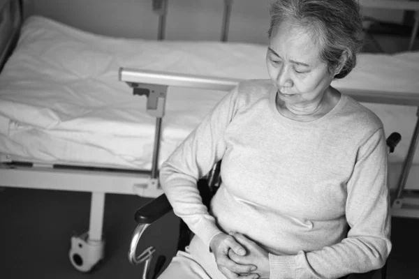 Hastane Yatağının Yanındaki Tekerlekli Sandalyede Oturan Üzgün Yaşlı Asyalı Kadının — Stok fotoğraf