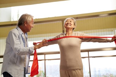 happy asian elderly couple exercising using resistance band in nursing home clipart