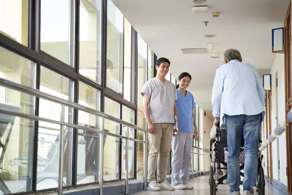 Happy Young Asian Physical Therapists Greeting Residents Hallway Nursing Home — Stock Photo, Image