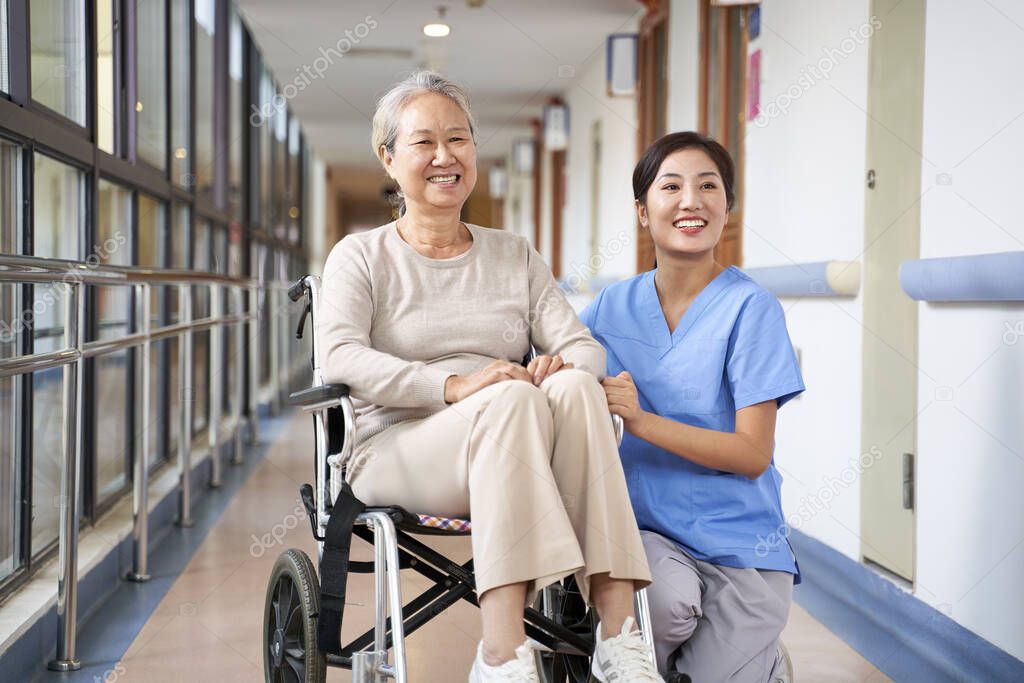 asian senior woman and her caregiver looking at camera smiling