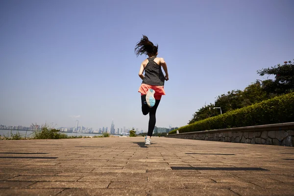 young asian adult woman running jogging outdoors, rear and low angle view