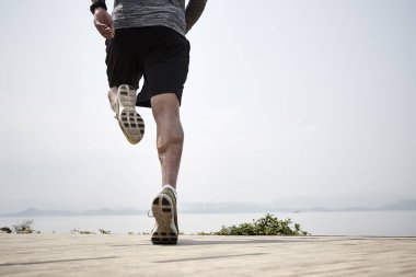 Asyalı bir koşucunun yakın plan çekimleri. Denizde, dikiz aynasından koşuyor.