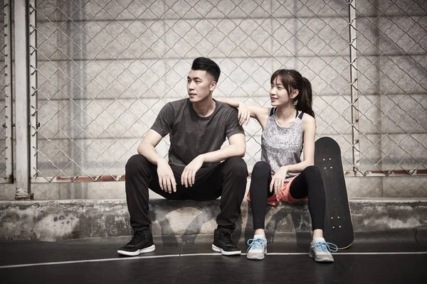若いアジア系の大人の男と女が運動後屋外でリラックス — ストック写真