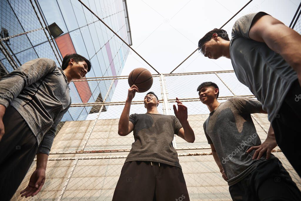 young asian adult men having fun playing with basketball outdoors