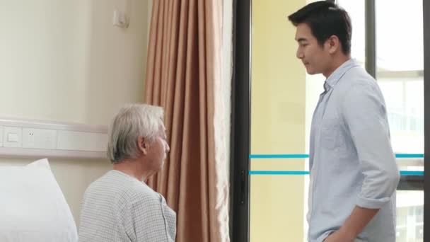 アジア系の成人の息子が病院病棟のお父さんと話をしたり — ストック動画