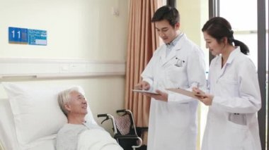 Genç Asyalı doktor viziteye çıkıyor ve hastane koğuşundaki kıdemli hastalarla konuşuyor.