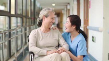 Dost canlısı Asyalı huzurevi çalışanı kıdemli bayan asistanla konuşuyor mutlu ve gülümsüyor