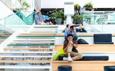 Bangkok, Tayland - 28 Kasım 2019: Bangkok 'taki Merkez Dünya Alışveriş Merkezi' nde merdivenlerin kenarında oturan yorgun yayalar.