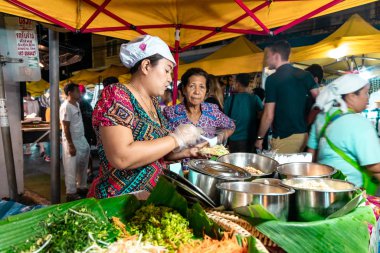 Yengeç Kasabası, Tayland - 23 Kasım 2019: Genç Taylandlı kadın Tayland 'ın Yengeç Kasabası' ndaki Krabi Hafta Sonu Gece Pazarı 'nda lezzetli Tayland yemekleri hazırlıyor.