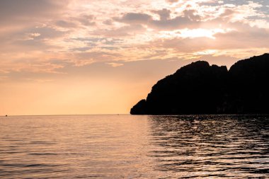 Gün batımında Phi Phi Adaları yakınlarındaki Andrea Denizi 'nin ortasındaki dramatik dağların silueti.