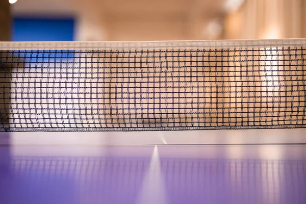 The net of the ping pong table. The net is placed in the center of the table, thus dividing the table in to two equal parts. selective focus