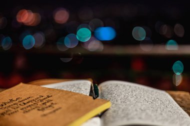 Bir akşam, şehrin odandan çıkarılmış ışıklarına karşı dışarıda duran bir günlük defteri. Blog yazarı öğrenci konsepti. seçici odak