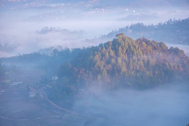 Arka planda, sisle kaplı tepelerin ve Büyük Himalaya Dağları 'nın kasvetli dramatik manzarası. Teras çiftçiliği