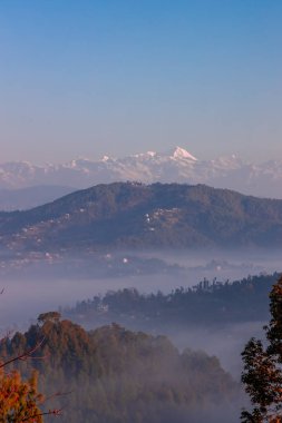 Arka planda, sisle kaplı tepelerin ve Büyük Himalaya Dağları 'nın kasvetli dramatik manzarası. Teras çiftçiliği