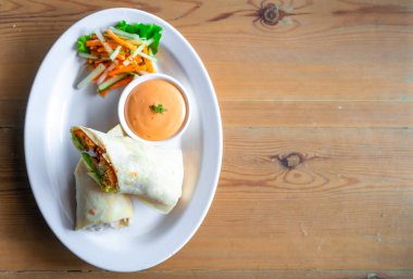 Mayoonaise soslu beyaz tabakta servis edilen Hint ekmeğinin içine sarılmış sebze dolmaları.